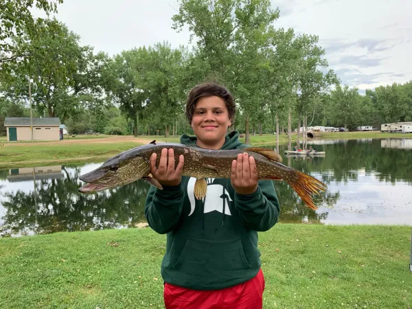 A young angler shows off a northern pike caught in the lake